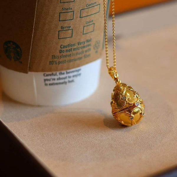 Treasure Egg Locket Ruby Necklace featuring an opening gold-plated egg locket that reveals a genuine ruby surrounded by sparkling zirconia accents.