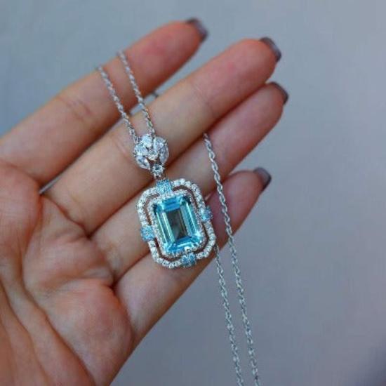 Vintage Blue Topaz Statement Pendant Necklace featuring a large emerald-cut blue topaz gemstone surrounded by sparkling accents in an ornate sterling silver setting.