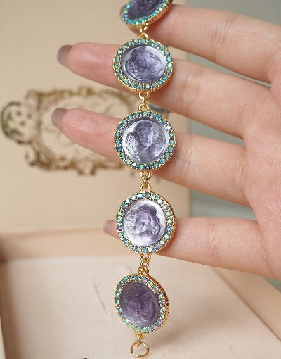 Celestial Cameo Crystal Bracelet with sculpted lavender angel face cameos, turquoise crystal halos, and a gold-plated vintage-inspired bracelet design.