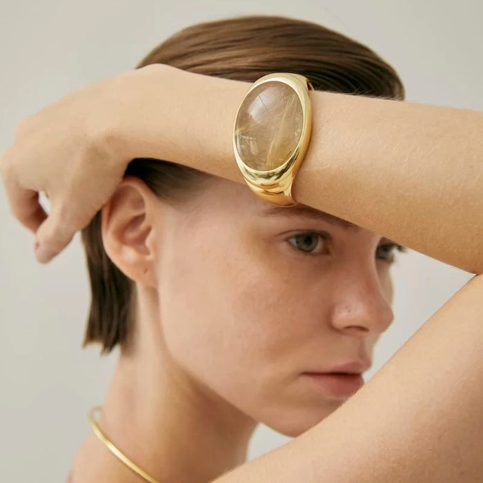 Bold Minimalist Gold Rutilated Quartz Wide Bangle featuring a large genuine gold rutilated quartz crystal framed within a sculptural gold-plated bracelet.