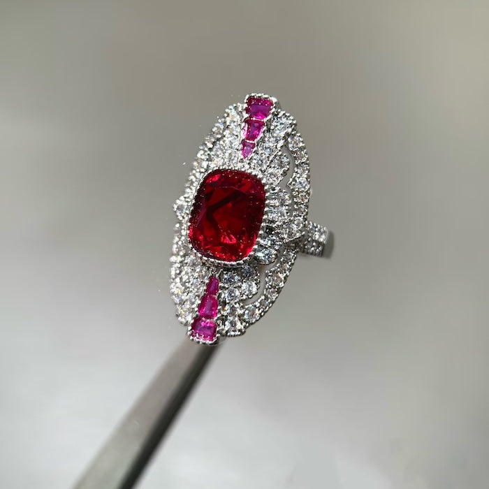 Art Deco Style Ruby Statement Ring featuring a ruby-red center stone, sparkling zirconia halo, and intricate vintage-inspired design in an adjustable setting.