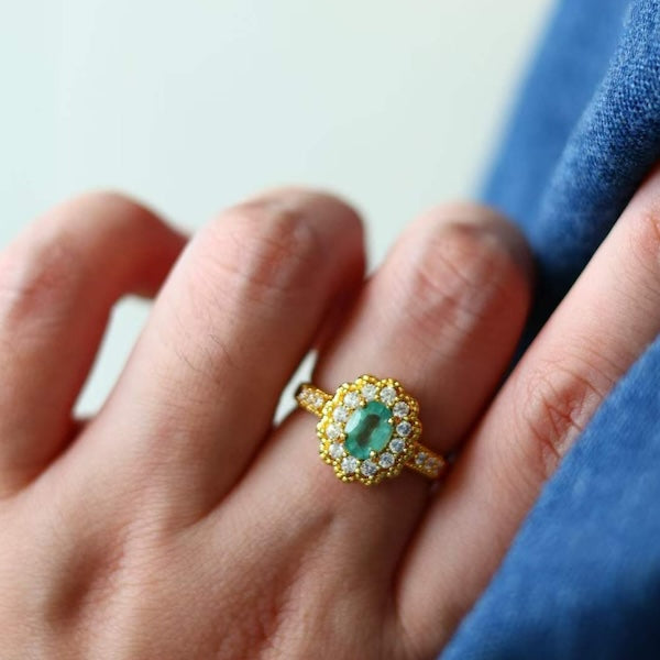 Vintage Emerald Blossom Ring featuring a genuine emerald gemstone surrounded by sparkling zirconia accents in a floral-inspired gold-plated setting.