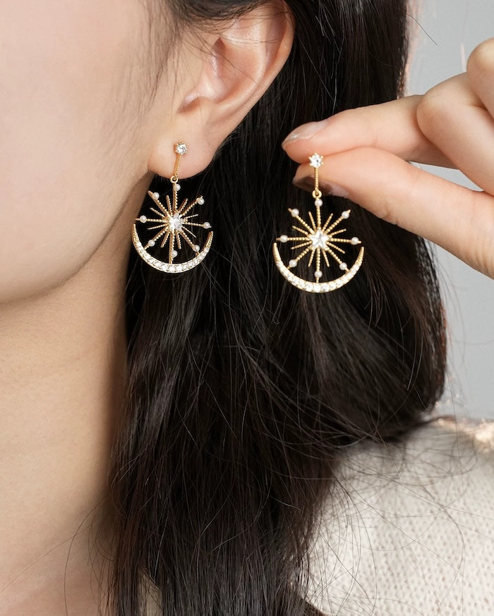 Celestial Moon & Star Drop Earrings featuring radiant starburst details, sparkling crystal accents, pearl embellishments, and a crescent moon silhouette in gold or silver plating.