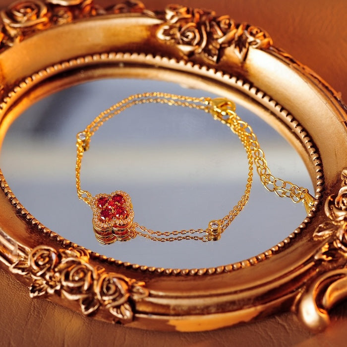 Turning Lucky Clover Jewelry Set featuring a rotating four-leaf clover with emerald green or ruby red crystals, pavé zirconia, and gold-plated settings in matching earrings, bracelet, and ring.