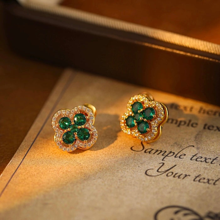 Turning Lucky Clover Jewelry Set featuring a rotating four-leaf clover with emerald green or ruby red crystals, pavé zirconia, and gold-plated settings in matching earrings, bracelet, and ring.