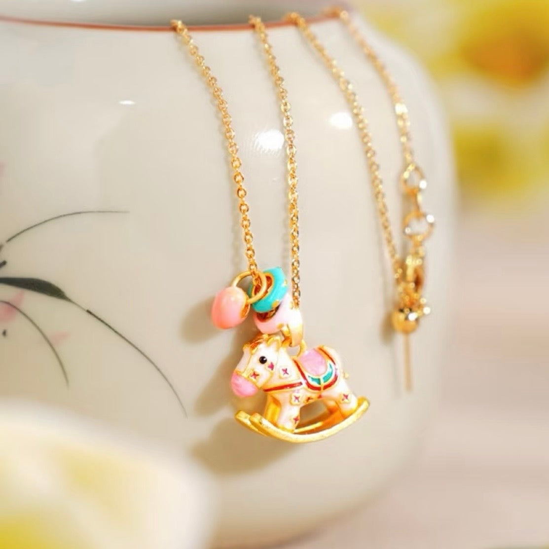 Enchanted Enamel Rocking Horse Charm Necklace with pastel rocking horse and miniature charms on a gold-plated chain.