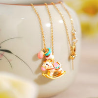Enchanted Enamel Rocking Horse Charm Necklace with pastel rocking horse and miniature charms on a gold-plated chain.
