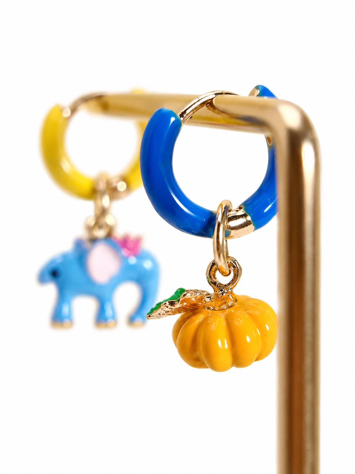 Enchanted Elephant & Pumpkin Enamel Hoop Earrings featuring a blue elephant charm and an orange pumpkin charm with vibrant hand-painted enamel on gold-plated brass hoops, measuring 3 × 1.5 cm.