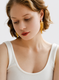 Golden cascading leaf earrings with layered curved leaves and white pearl studs.