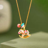 Enchanted Enamel Rocking Horse Charm Necklace with pastel rocking horse and miniature charms on a gold-plated chain.