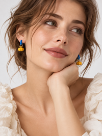 Enchanted Elephant & Pumpkin Enamel Hoop Earrings featuring a blue elephant charm and an orange pumpkin charm with vibrant hand-painted enamel on gold-plated brass hoops, measuring 3 × 1.5 cm.