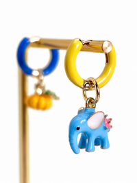Enchanted Elephant & Pumpkin Enamel Hoop Earrings featuring a blue elephant charm and an orange pumpkin charm with vibrant hand-painted enamel on gold-plated brass hoops, measuring 3 × 1.5 cm.