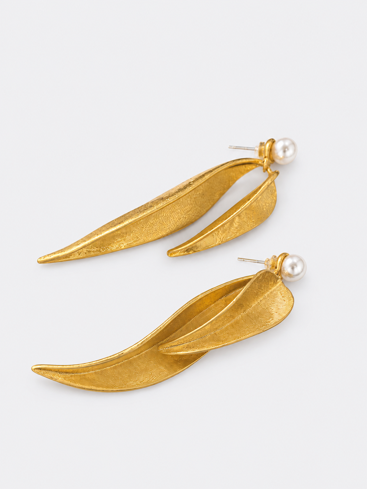 Golden cascading leaf earrings with layered curved leaves and white pearl studs.