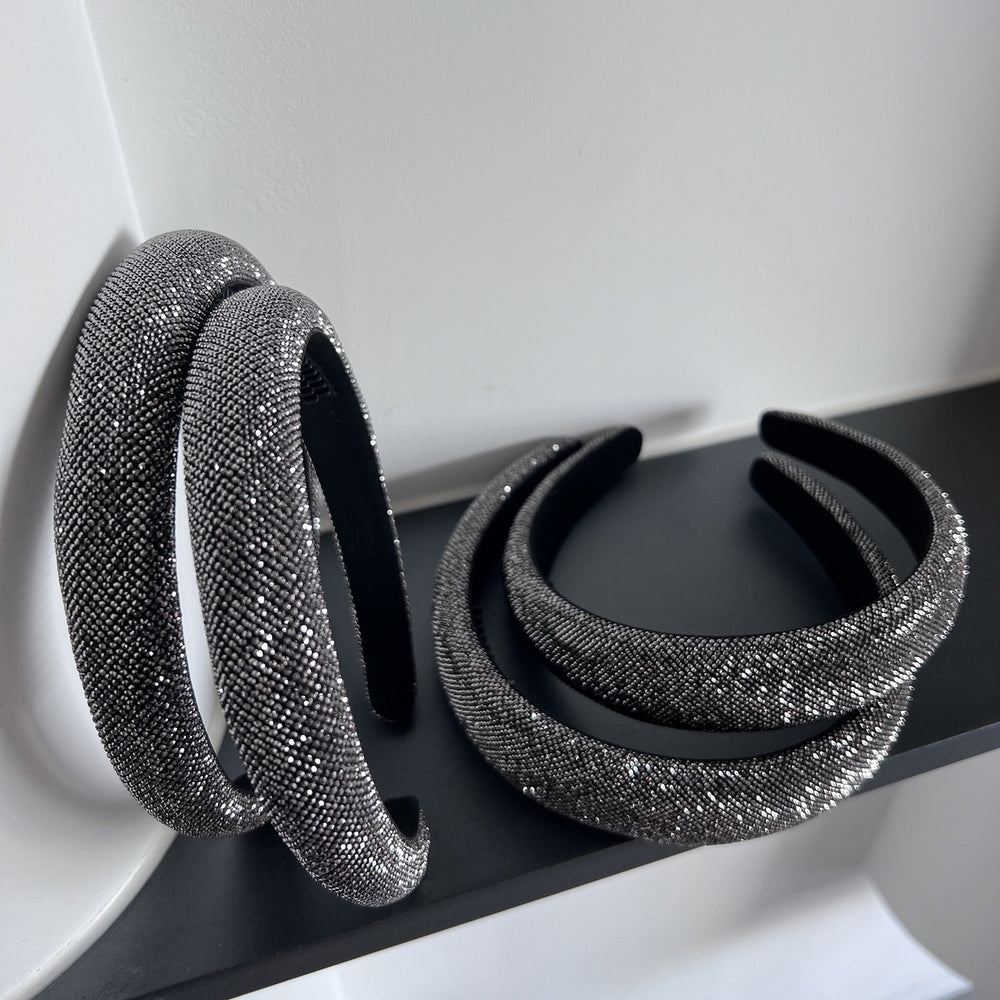 Dark silver pavé crystal padded headband with all-over sparkling embellishments and a sculptural curved silhouette.