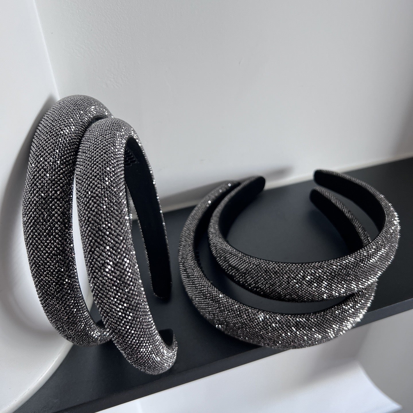 Dark silver pavé crystal padded headband with all-over sparkling embellishments and a sculptural curved silhouette.