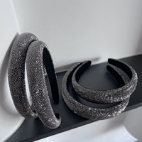 Dark silver pavé crystal padded headband with all-over sparkling embellishments and a sculptural curved silhouette.