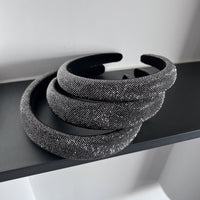 Dark silver pavé crystal padded headband with all-over sparkling embellishments and a sculptural curved silhouette.