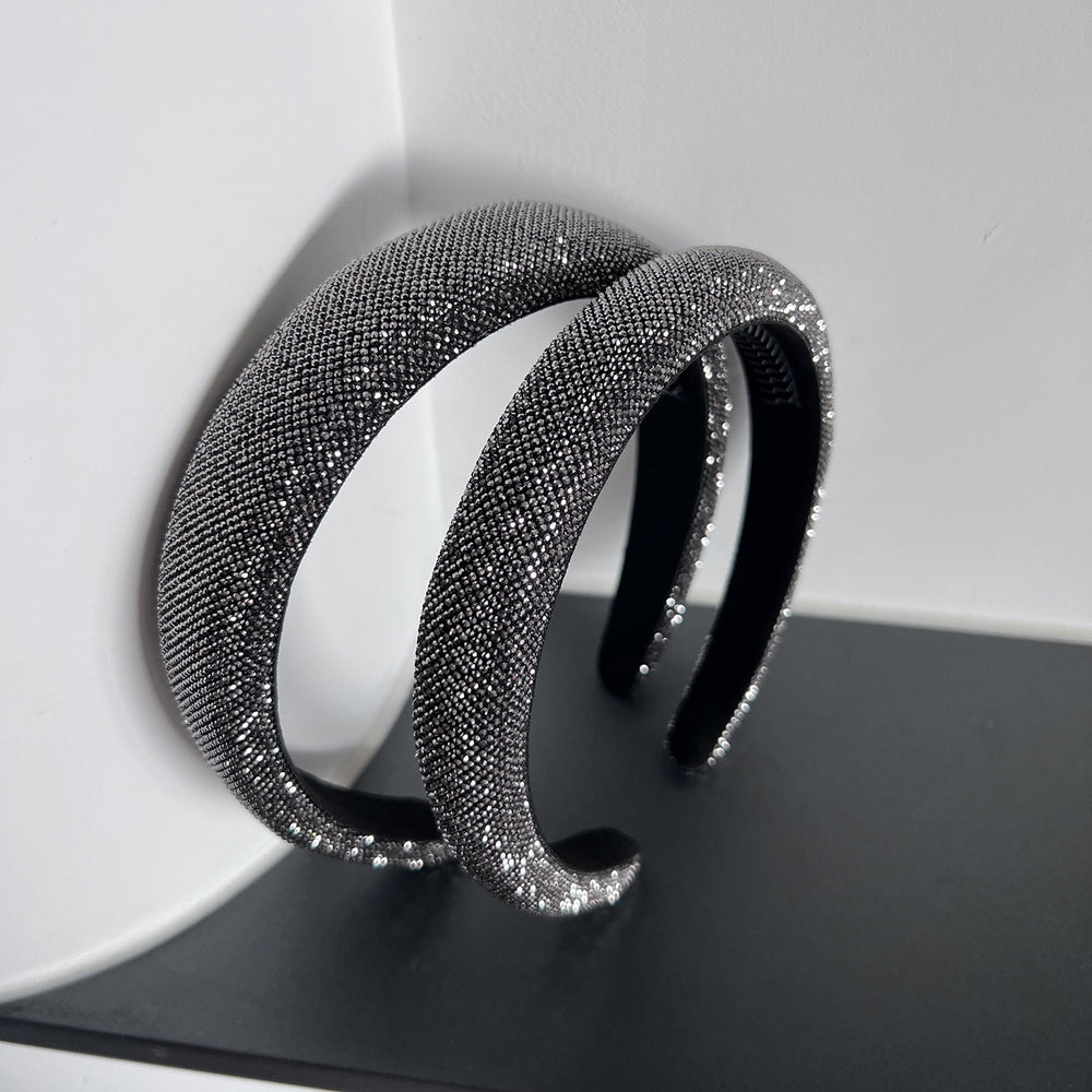Dark silver pavé crystal padded headband with all-over sparkling embellishments and a sculptural curved silhouette.