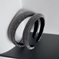 Dark silver pavé crystal padded headband with all-over sparkling embellishments and a sculptural curved silhouette.