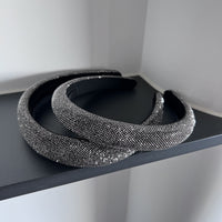 Dark silver pavé crystal padded headband with all-over sparkling embellishments and a sculptural curved silhouette.