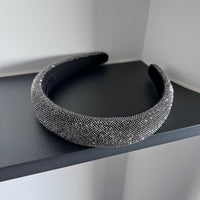 Dark silver pavé crystal padded headband with all-over sparkling embellishments and a sculptural curved silhouette.