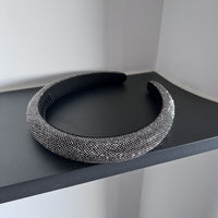 Dark silver pavé crystal padded headband with all-over sparkling embellishments and a sculptural curved silhouette.
