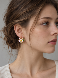 Golden Twin Daisy Hoop Earrings featuring one green enamel daisy and one soft pink enamel daisy suspended from polished gold-tone hoops.