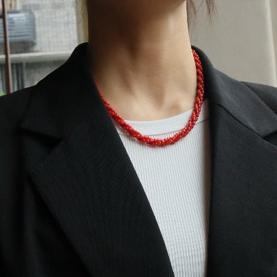 Artisan Coral Braided Necklace featuring multiple strands of genuine red coral beads intricately woven into an elegant braided necklace design with a sterling silver clasp.