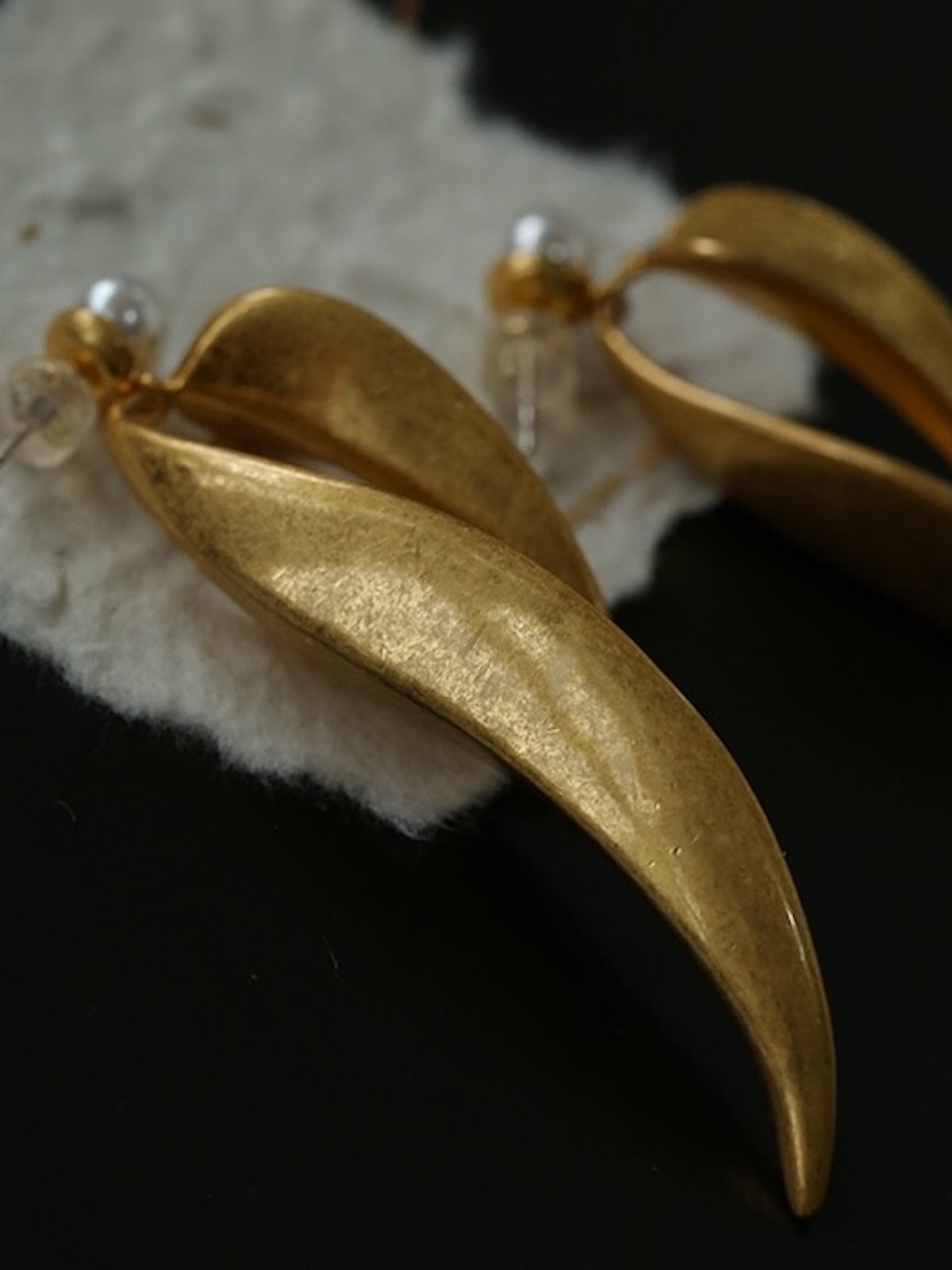 Golden cascading leaf earrings with layered curved leaves and white pearl studs.