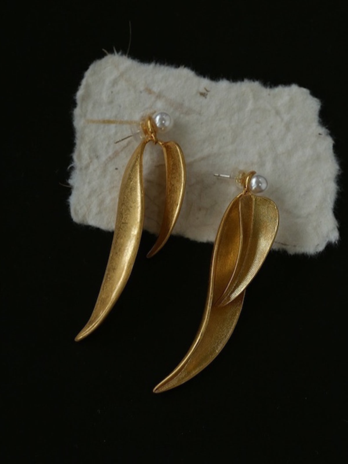 Golden cascading leaf earrings with layered curved leaves and white pearl studs.
