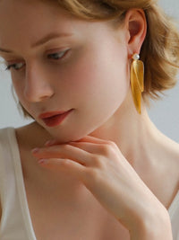 Golden cascading leaf earrings with layered curved leaves and white pearl studs.
