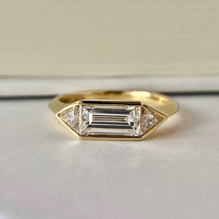 Radiant 3-Stone Moissanite Ring featuring a 1.4 ct emerald-cut center moissanite flanked by two side stones in an elegant gold vermeil setting.
