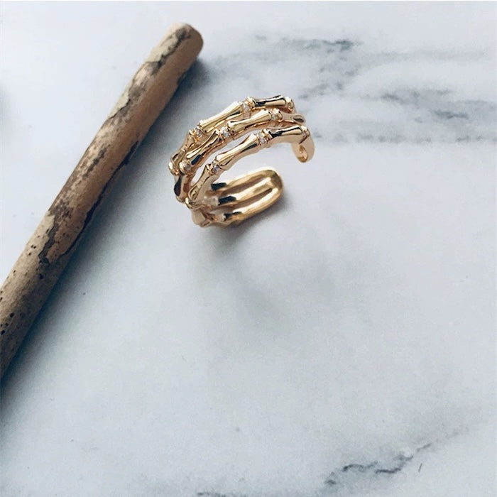 Layered Bamboo Style Adjustable Ring featuring multiple bamboo-inspired gold-tone bands stacked into a bold adjustable ring design.
