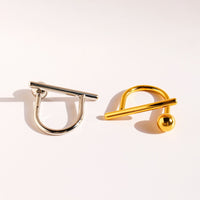 Sculptural Beam and Dot Ring featuring a contemporary geometric design with a polished bar and sphere detail, available in gold and silver-tone finishes.
