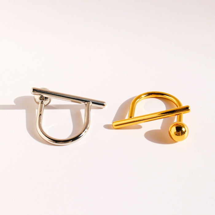 Sculptural Beam and Dot Ring featuring a contemporary geometric design with a polished bar and sphere detail, available in gold and silver-tone finishes.
