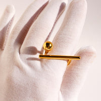 Sculptural Beam and Dot Ring featuring a contemporary geometric design with a polished bar and sphere detail, available in gold and silver-tone finishes.
