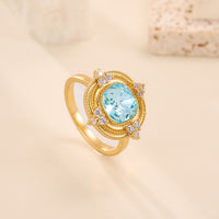 Royal Style Sky Blue Stone Ring featuring a sparkling sky-blue center stone surrounded by zirconia accents in a gold-plated vintage-inspired halo design.
