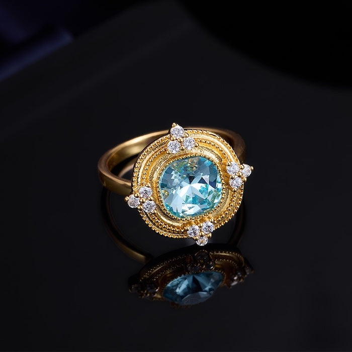 Royal Style Sky Blue Stone Ring featuring a sparkling sky-blue center stone surrounded by zirconia accents in a gold-plated vintage-inspired halo design.
