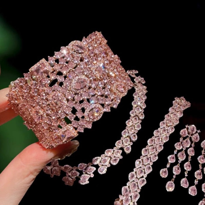 Blush Diamond Couture Jewelry Set featuring an open rose gold-plated cuff bangle, matching tennis bracelet, and cascading chandelier earrings adorned with brilliant blush pink stones.
