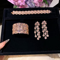 Blush Diamond Couture Jewelry Set featuring an open rose gold-plated cuff bangle, matching tennis bracelet, and cascading chandelier earrings adorned with brilliant blush pink stones.