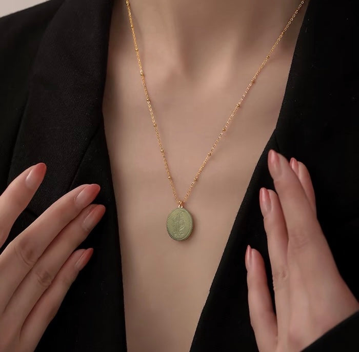 Vintage Botanical Mother of Pearl Medallion Necklace with an engraved floral pendant in powder blue, sage green, or lavender on a gold-plated stainless steel chain.
