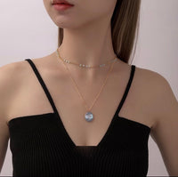Vintage Botanical Mother of Pearl Medallion Necklace with an engraved floral pendant in powder blue, sage green, or lavender on a gold-plated stainless steel chain.
