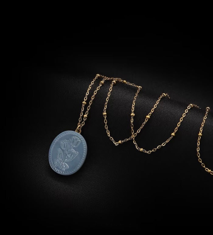 Vintage Botanical Mother of Pearl Medallion Necklace with an engraved floral pendant in powder blue, sage green, or lavender on a gold-plated stainless steel chain.
