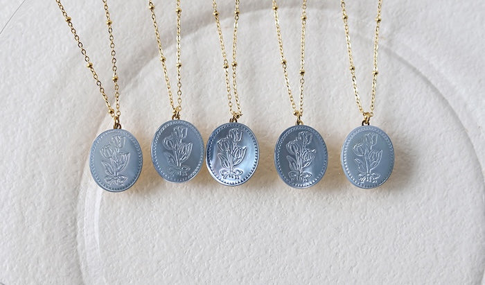 Vintage Botanical Mother of Pearl Medallion Necklace with an engraved floral pendant in powder blue, sage green, or lavender on a gold-plated stainless steel chain.
