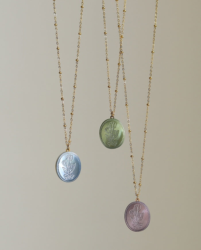 Vintage Botanical Mother of Pearl Medallion Necklace with an engraved floral pendant in powder blue, sage green, or lavender on a gold-plated stainless steel chain.
