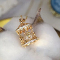 Luxe Carousel Pearl Pendant Necklace featuring a luminous pearl suspended inside an intricately detailed carousel pendant with sparkling accents and a gold-tone finish on a 40 + 5 cm chain.