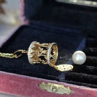 Luxe Carousel Pearl Pendant Necklace featuring a luminous pearl suspended inside an intricately detailed carousel pendant with sparkling accents and a gold-tone finish on a 40 + 5 cm chain.