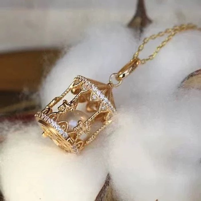 Luxe Carousel Pearl Pendant Necklace featuring a luminous pearl suspended inside an intricately detailed carousel pendant with sparkling accents and a gold-tone finish on a 40 + 5 cm chain.