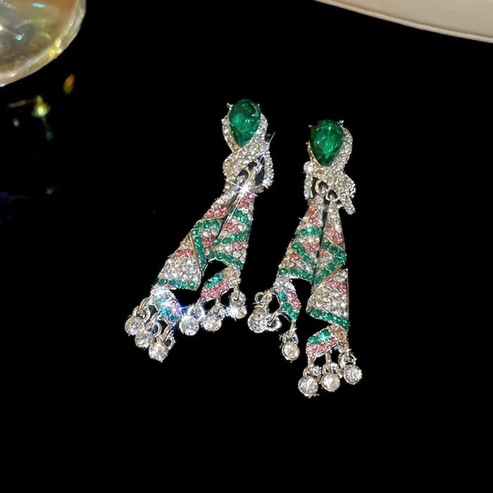 Emerald Ribbon Cascade Earrings with an emerald green teardrop crystal, silver-plated finish, sparkling zirconia, ribbon-inspired detailing, and crystal tassels.