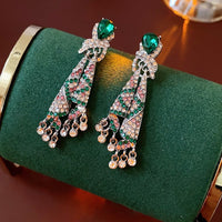 Emerald Ribbon Cascade Earrings with an emerald green teardrop crystal, silver-plated finish, sparkling zirconia, ribbon-inspired detailing, and crystal tassels.